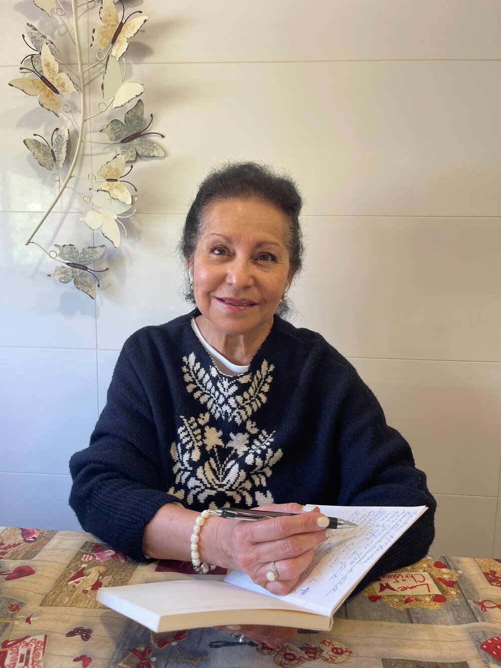 Inés Olimpia Salazar — retrato escribiendo, con mariposas decorativas al fondo